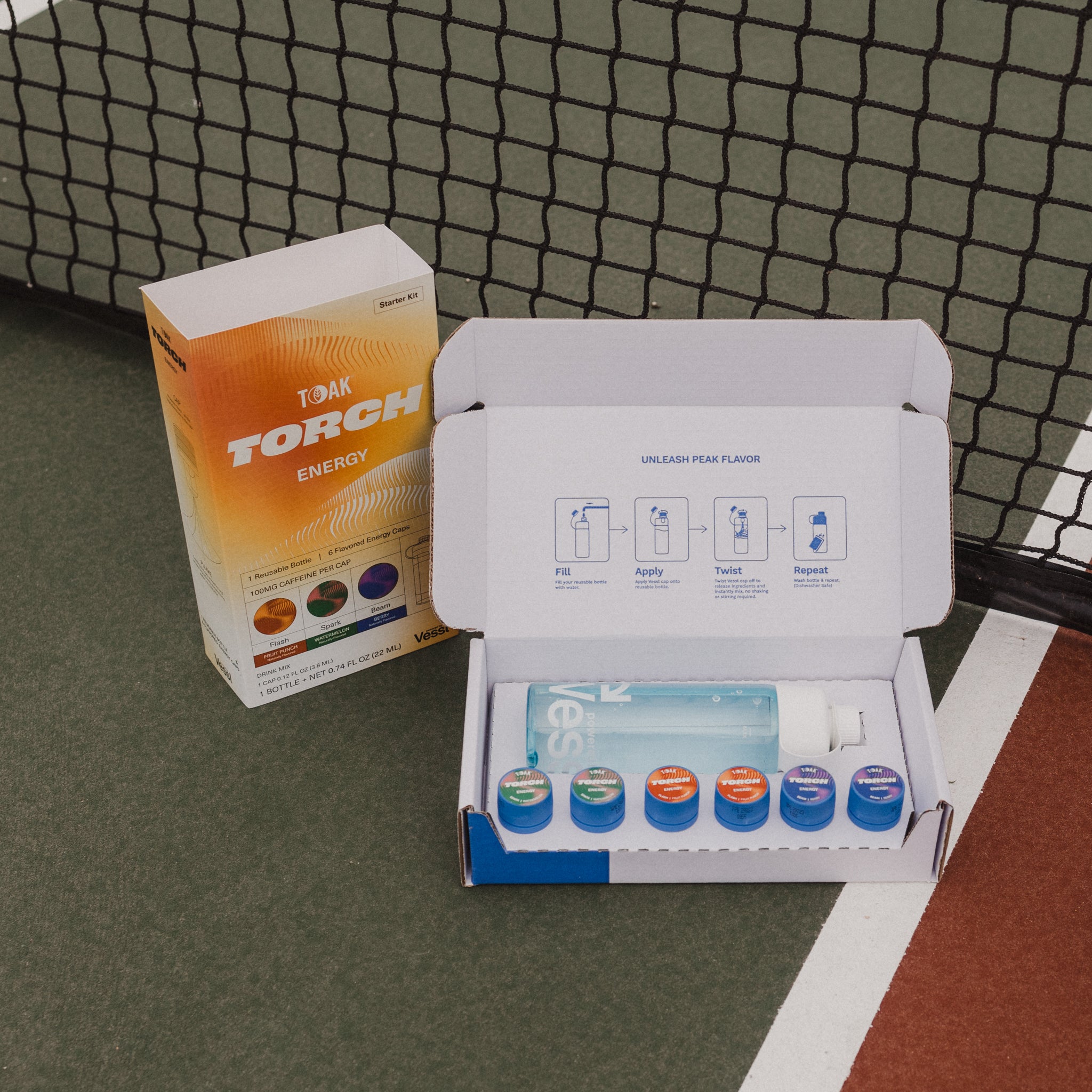 Box of TOAK products with a Torch Energy drink mix box on a sports court background