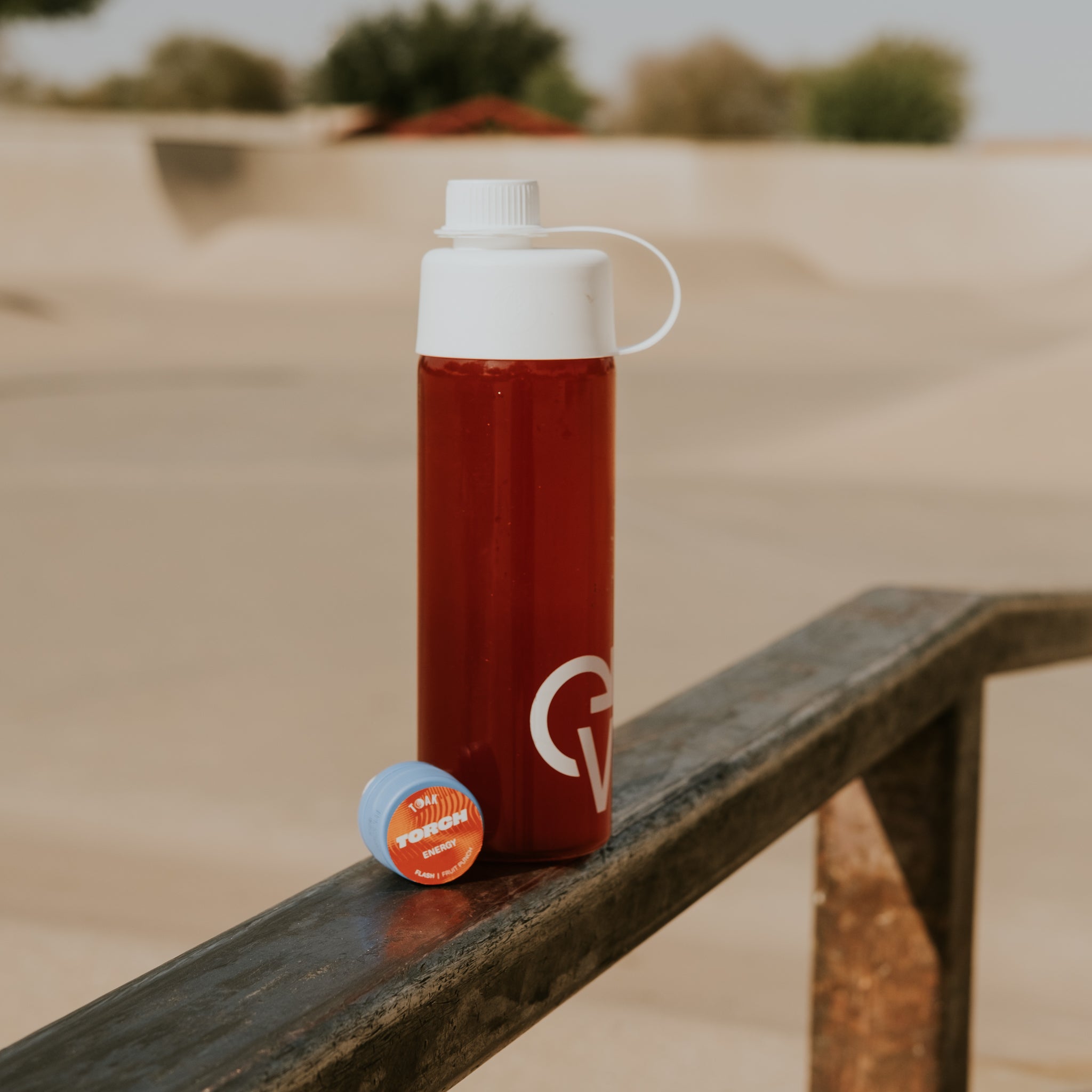 Red water bottle with a white cap on a metal surface outdoors