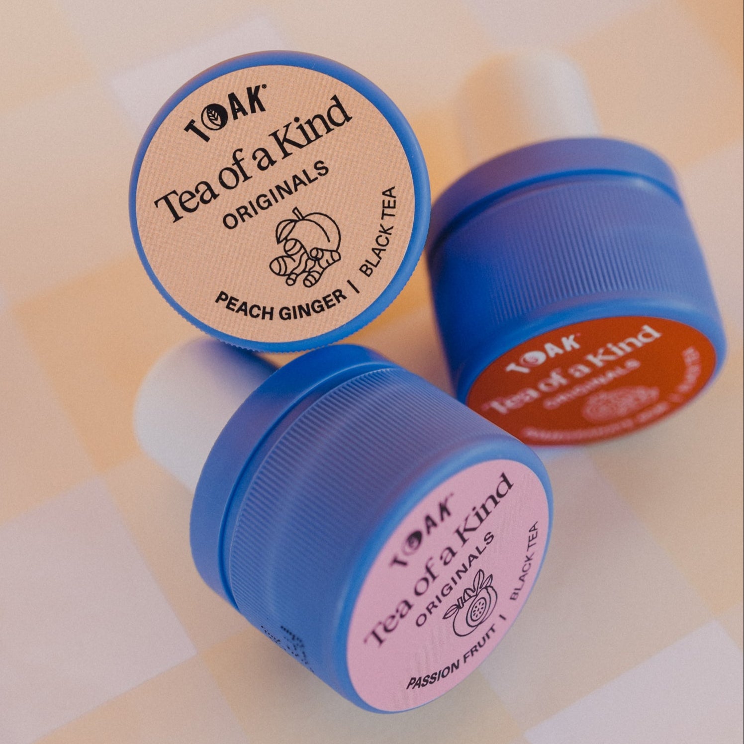 Three caps of TOAK originals on a checkered background
